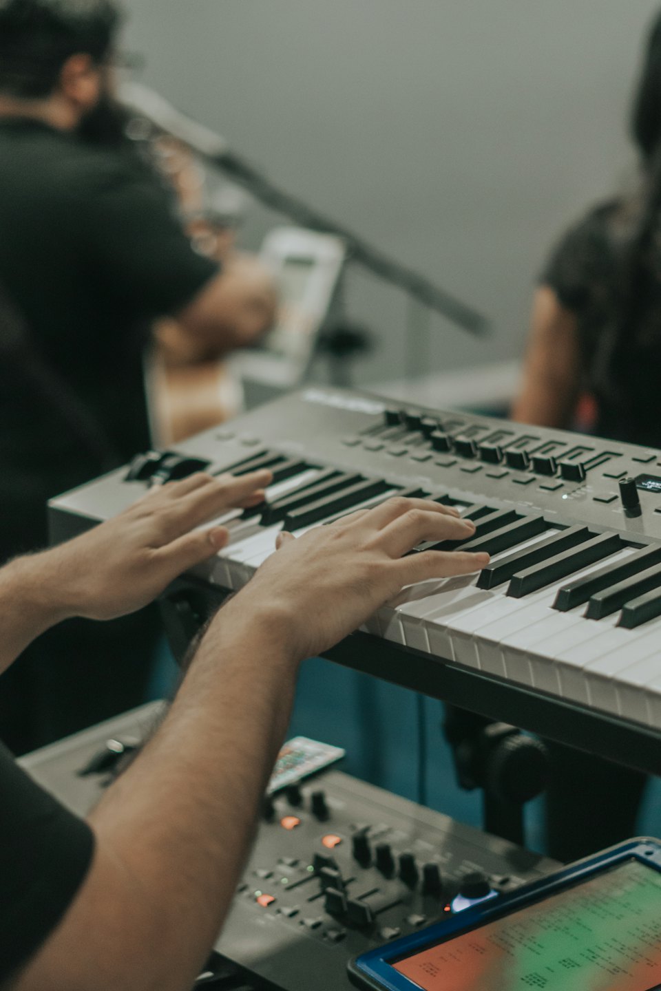 Fingers playing a digital piano with control knobs.